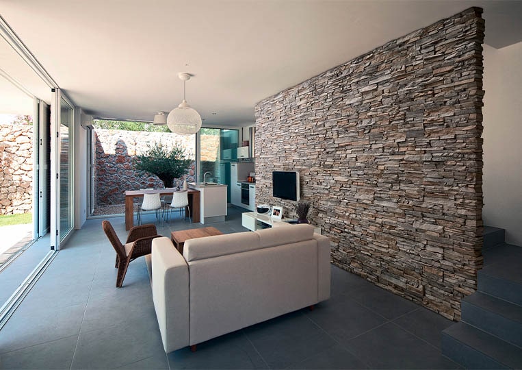 salon intérieur avec un pant de mur en pierre de parement acl siena gris